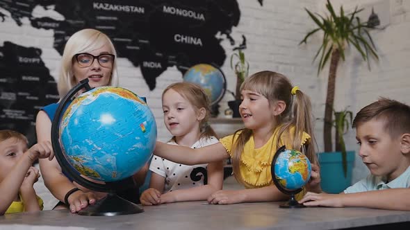 Teacher Looks at Globes in Geography Classroom on the Lesson at the Elementary School