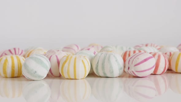 Colorful striped bonbons on white 4K tilting footage