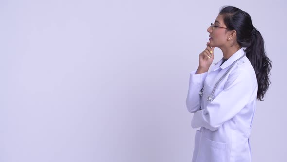 Profile View of Young Happy Persian Woman Doctor Thinking