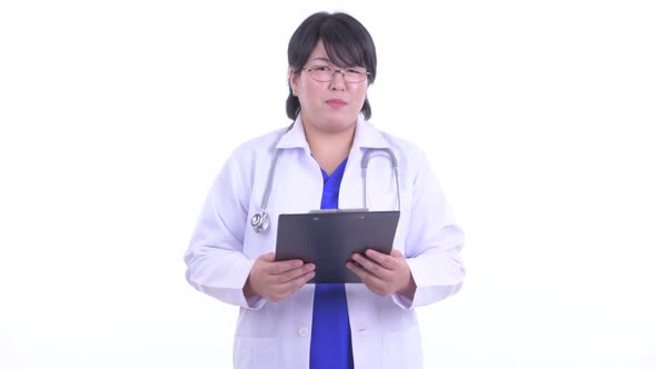 Happy Overweight Asian Woman Doctor Talking While Holding Clipboard