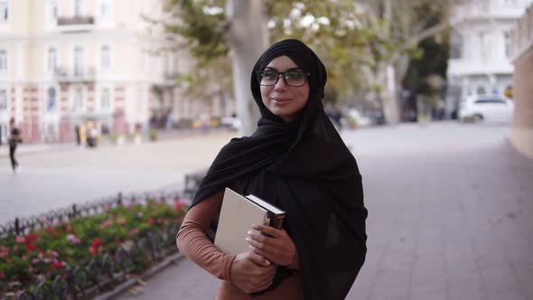 Confident Attractive Muslim Woman in Hijab and Glasses Walking By Streetclose to the College or