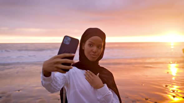 Somali-American woman taking a selfie at the beach