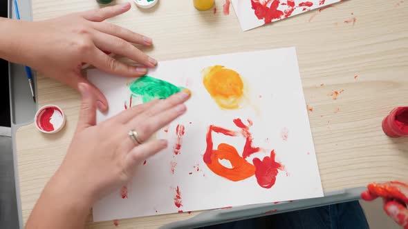 Top View of Little Boy with Mother Drawing and Painting with Hands Covered in Colorful Paint on