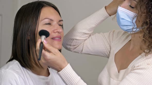 Make Up Artist Applies Powder on Pretty Woman's Face Using Brush in Beauty Salon