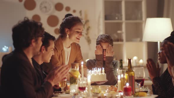 Happy Woman Blowing Candles on Birthday Cake at Dinner Party