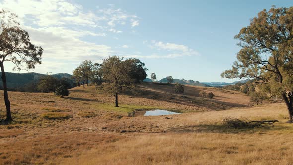 Slow paced forward aerial tracking shot over a small dam in beautiful Australian scenery.