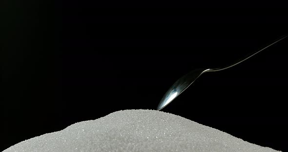 Spoon falling on Powder Sugar against Black Background, Slow Motion 4K