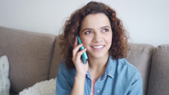 Multiethnic Young Woman Talking with Friends on Mobile Phone Sitting at Home