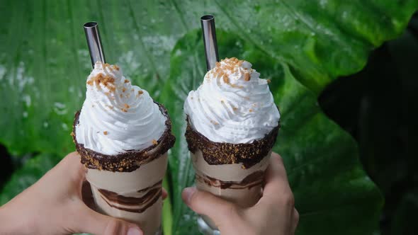 Close Up of Two Yummy Cacao Milkshakes with Chocolate Syrup Sweet Whipped Cream and Cookies