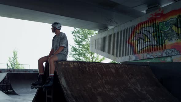 Relaxed Roller Skater Resting on Ramp at Skatepark