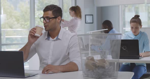 Young Indian Businessman Throwing Coffee Cup Into Waste Bin in Office