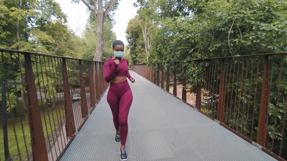 Black Fitness Woman Running on Bridge in Protective Medical Mask