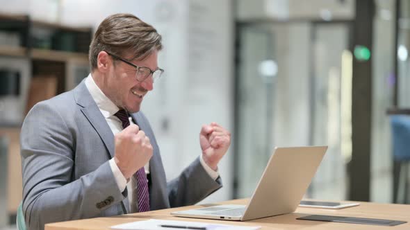 Excited Businessman Celebrating Success on Laptop in Office 