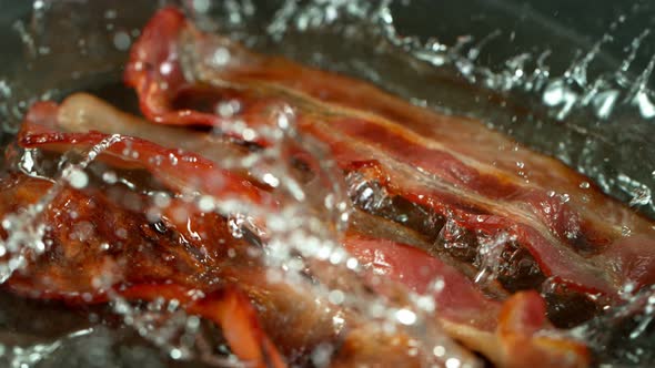 Super Slow Motion Shot of Roasted Bacon Slices Falling Into Pan at 1000 Fps