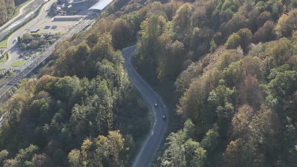 Aerial View Two Automobile Riding on Highway Mountain Serpentine Road Sun Lights at Village Resort