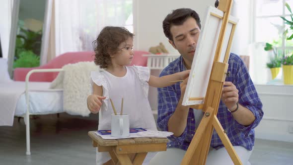 Happy family of father and kid drawing picture, using different paints and brushes. 