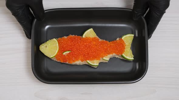 Sandwich with red caviar in shape of fish with lemon put on plate. Seafood