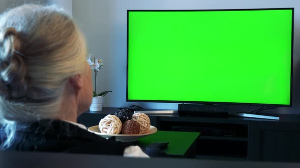 Old Caucasian Woman Watches Television in Living Room - Green Screen - Closeup