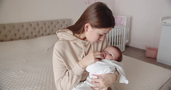 Caring Mother Lulls Baby In Her Arms