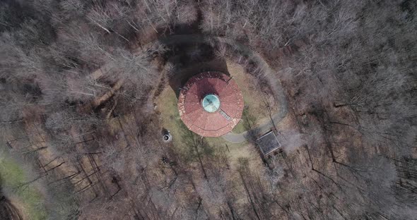 Moving Down Overhead Above Building or Church in Middle of Bare Woods Forest in Autumn or Winter