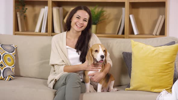 Joyous Female Owner Posing with Lovely Beagle Puppy on Sofa