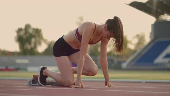 Caucasian Young Brunette Woman Shit for a Run in the Stadium Comes Up to the Running Sides and