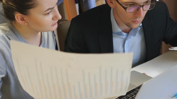 Group of Young Colleagues Comparing Sales Result Graph on Paper with Chart on Computer Screen at