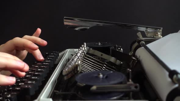 The girl is typing on a retro typewriter. Slow motion.