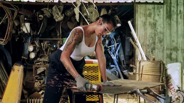 Attractive young woman mechanical worker repairing a vintage car in old garage.