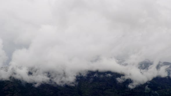 Group of Large White Clouds Covering Mountain Peak