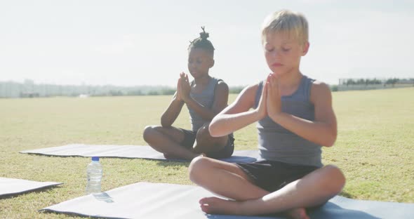 Video of focused diverse boys practicing yoga on mats on sunny day