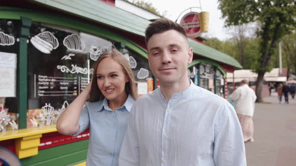 A Young Romantic Couple Hold Hands and Goes Along the Street Along the Small Shopping Stalls and