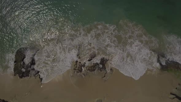 Top view of waves break on stones. Pantai Pemutih beach, Bali, Indonesia