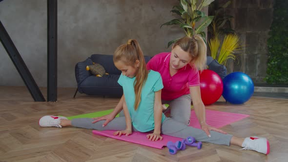 Caring Mother Helping Child Doing Side Splits Indoors