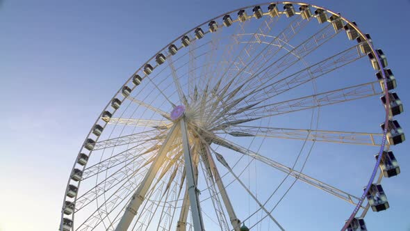 Majestic Observation Wheel Rotating in Amusement Park, Sunny Blue Sky Background