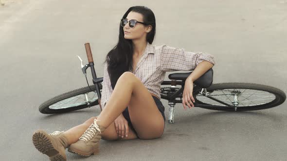 Young Woman Sitting with a Bicycle Outdoor