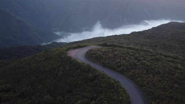 A winding road with low clouds at sunset in Fanal, Madeira. Shot on DJI.