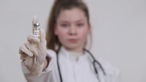 Blurred Caucasian Future Doctor Stretching Hand with Covid19 Vaccine Jab Closeup