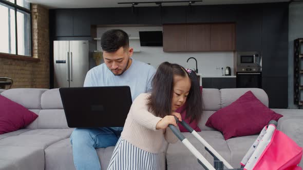 Asian Father Working and Nursing Toddler Daughter at Home