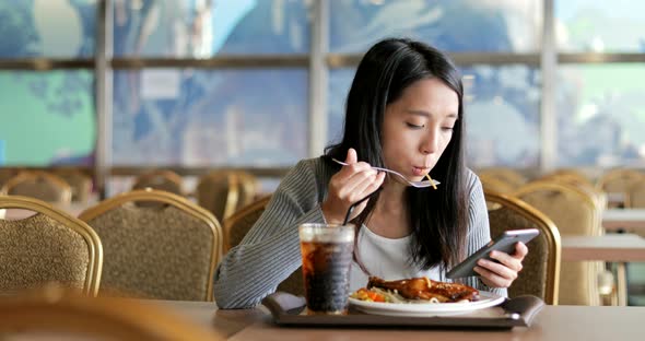 Woman using cellphone and having lunch in restaurant 