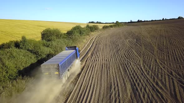 Aerial View of a Truck Driving on Dirt Road Between Plowed Fields Making Lot of Dust