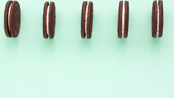 Sweet brown cookies with white cream inside move back and forth on bright blue background on the top alt