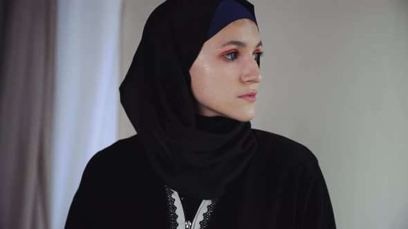 Thoughtful Muslim Woman in Traditional Arabian Abaya Dress on Gray Background