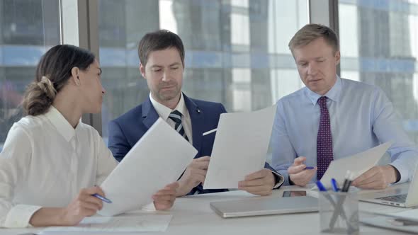 Executive Business People Having Arguments on Documents While Sitting on Office Table