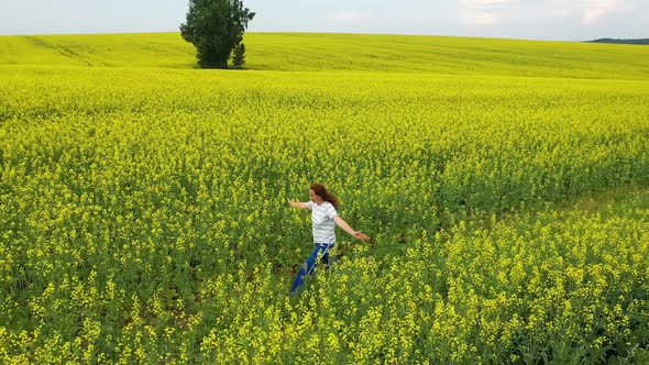 The Girl Runs on a Yellow Flower Field at Sunset 