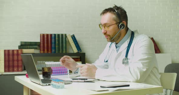 A Doctor is Talking to a Colleague Via Video Link About the Latest Research He is Drinking Coffee