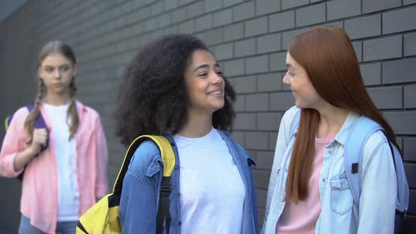 Two Schoolgirls Making Fun of Female Student Standing Aside Spreading Rumors