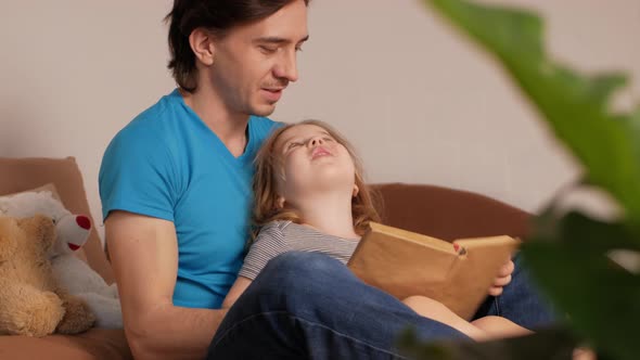 Dad and Daughter Read Book on Bed in Bedroom Process of Learning and Upbringing Little Girl Child