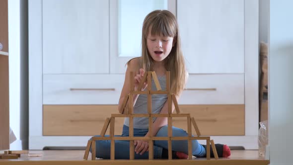Happy Child Girl Playing Game Stacking Wooden Toy Blocks in High Pile Structure