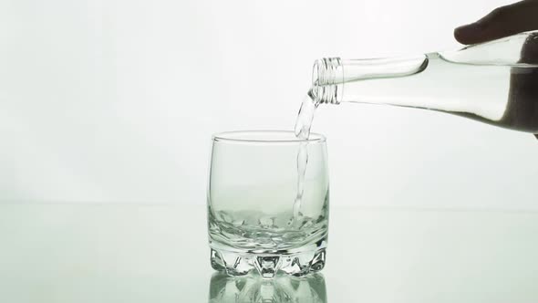 Water Is Pouring From Bottle Into Glass